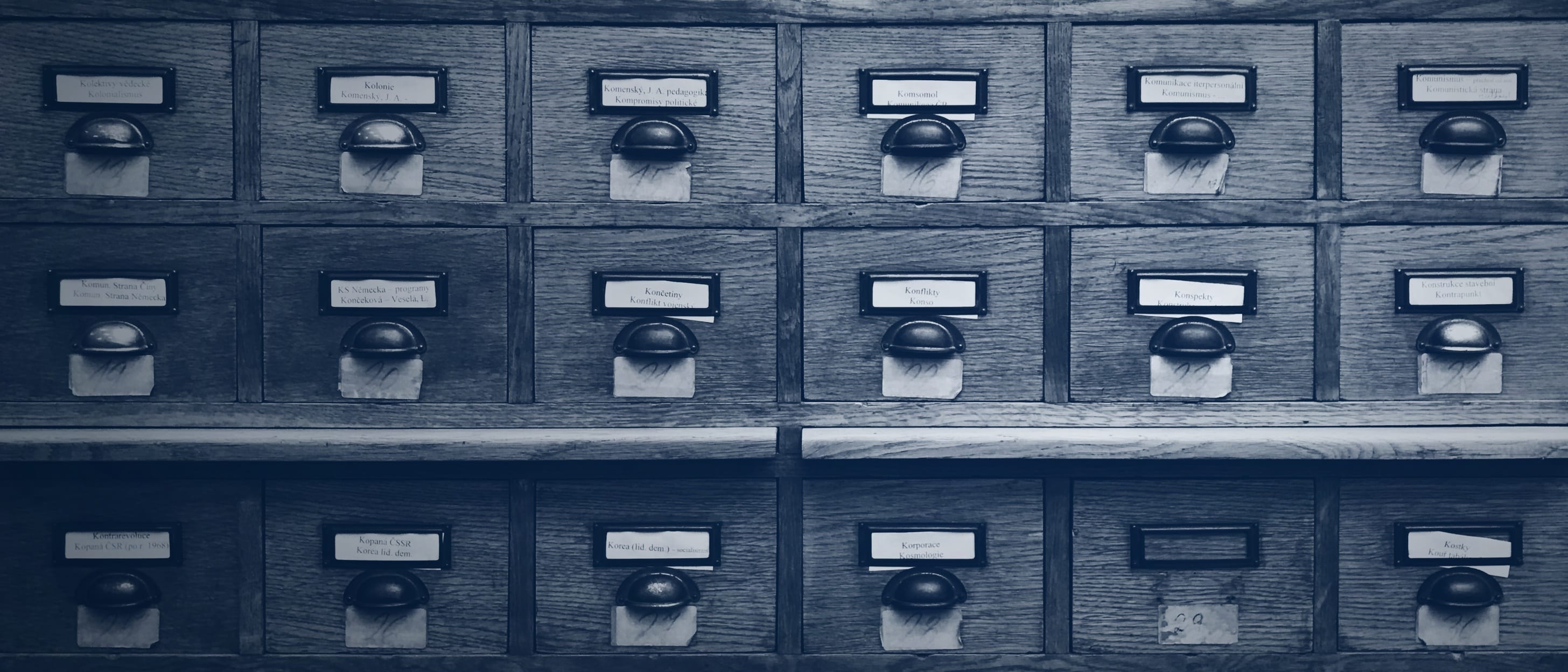 A wooden card catalogue with many labelled drawers and metal handles - nobody is shown.