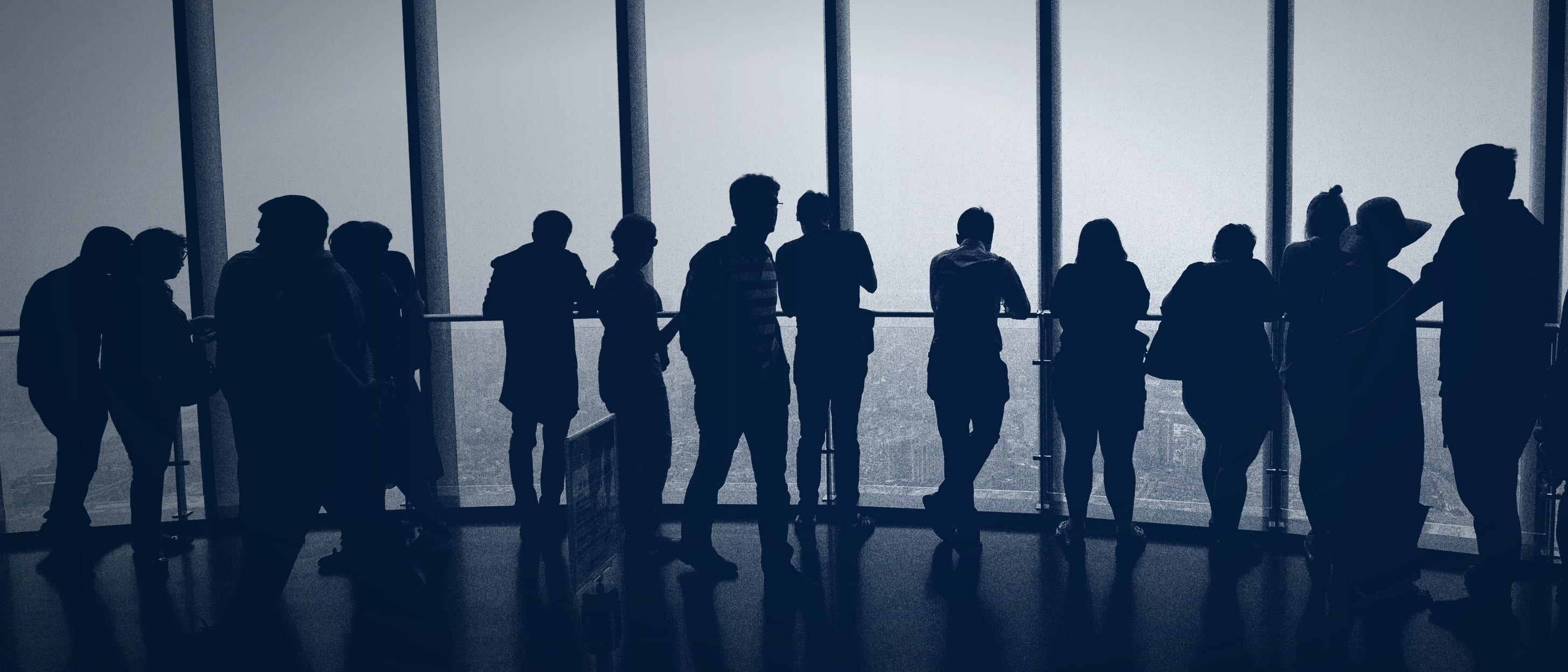 Menschen als dunkle Silhouetten vor einer hellen Fensterfront: Die Personen sind zählbar, aber niemand ist zu erkennen.