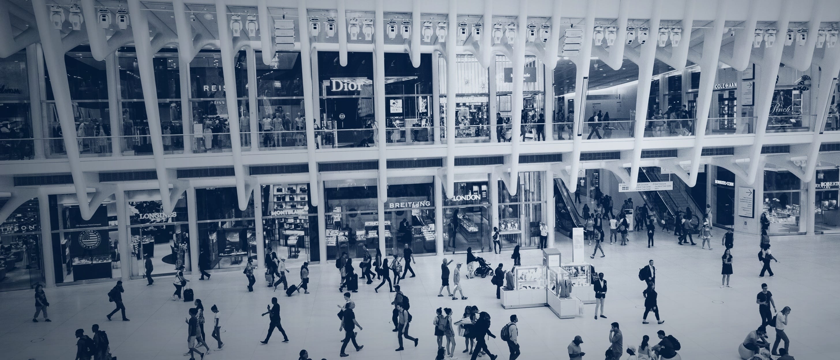 A large hall seen from above: some people are walking purposefully through it while others stand together in groups - no individual is identifiable.
